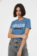 Remera de algodón color azul, con cuello redondo y mangas cortas. Presenta un estampado frontal con la frase 'URUGUAY noma!' en letras blancas y negras.