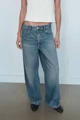 Jeans de tiro medio con diseño baggy barrel, cinco bolsillos y costuras laterales curvadas. Presenta cierre frontal con cremallera y botón metálico.