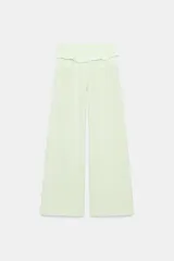 Pantalón verde claro de tiro medio, con bolsillos delanteros y cintura ajustable con cordones y volantes del mismo tejido.