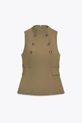 Top sin mangas de cuello subido, con diseño entallado y cierre de cremallera en la espalda. Presenta doble botonadura frontal decorativa y detalle de trabillas laterales en la cintura.
