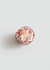 Vincha de poliéster color blanco con diseño floral plisado y detalles en color rojo en los bordes.