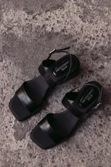 Sandalia de cuero color beige claro (off white) con taco ancho y tiras finas ajustables con hebilla metálica dorada en el tobillo.