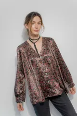 Camisa de seda con estampado floral en tonos bordó, marrón y negro. Presenta un corte amplio, escote en V con cierre frontal de botones, mangas largas abullonadas y detalles de frunce en hombros y espalda.