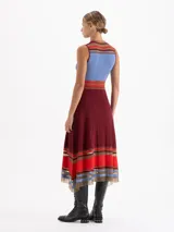 Vestido midi de punto sin mangas con diseño plisado. Presenta un corte evasé con rayas horizontales en tonos rojo, rosa y negro en el cuello, la cintura y el ruedo, el cual cuenta con terminaciones irregulares y detalles de transparencia.