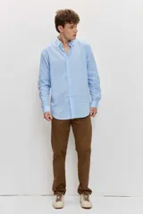 Camisa celeste de manga larga con cuello camisero abotonado y cierre frontal con botones.