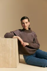 Polera de tejido acanalado en color marrón con detalles de líneas en tono lila, cuello alto y mangas largas con diseño raglán.