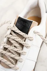 Zapatillas bajas de cuero blanco con puntera y talón en gamuza color beige. Ajuste con cordones y suela marrón.