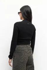 Polera gris de tejido tramado, manga larga y cuello alto.