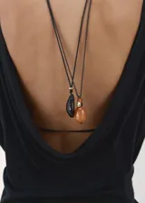 Chaleco de punto fino semitransparente color negro, con diseño recto, cuello redondo y manga larga. Presenta espalda abierta y drapeada, sin cierre.