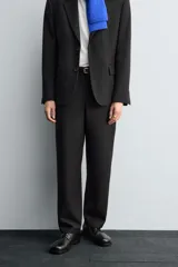 Pantalón de traje corte straight fit confeccionado en tejido mezcla de lana. Presenta cierre frontal con cremallera y botón, bolsillos laterales y bolsillos traseros de vivo.
