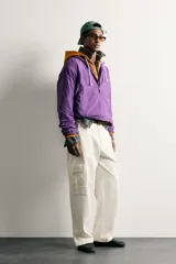 Chaqueta canguro técnica de corte relaxed fit en color violeta, con cuello subido ajustable, cierre frontal de cremallera parcial, manga larga y bolsillos frontales con cierre y tipo canguro.