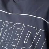 Remera gris oscuro de corte boxy, manga corta amplia, con cuello redondo y diseño gráfico frontal con la palabra "CONCEPTO" delineada en blanco dentro de un panel horizontal.