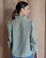Blusa de algodón color azul, de corte suelto, con mangas largas abullonadas y cuello con volados y escote en V.