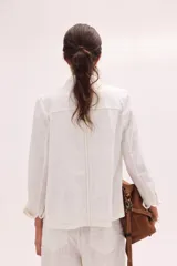 Chaqueta de lino lavado color blanco, con cuello mao, cierre metálico diagonal y detalles en contratono.