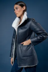 Campera reversible de cuero ovino, color azul marino, con interior de piel sintética blanca. Presenta cuello alto, cierre frontal y bolsillos frontales aplicados.