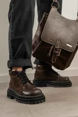 Borcegos de punta cuadrada con diseño acordonado, combinando paneles de cuero texturizado y gamuza en tonos marrones. Presentan una suela track gruesa de goma negra y cordones negros.