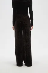 Pantalon de corte ancho y tiro alto, confeccionado en tela de terciopelo con acabado brillante. Presenta cintura elástica y pinzas frontales que aportan volumen y caída fluida a la prenda.