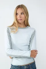 Remera de manga larga color blanco melange, con cuello redondo y diseño acanalado rib 2x2. Presenta un fit ajustado que acompaña la silueta.