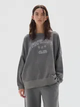 Buzo de felpa de algodón con efecto lavado, corte oversize, cuello redondo y estampa frontal con texto y estrellas.