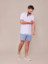 Remera polo blanca de manga corta, con detalles en azul marino en el cuello y los puños, y el logo bordado en el pecho.