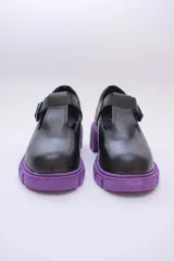 Guillermina de cuero negra con suela tractorada roja y hebilla dorada.