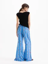 Pantalón de corte holgado y piernas rectas, confeccionado en popelina satinada de color celeste con estampado floral en franjas verticales. Cuenta con cintura elastizada y bolsillos delanteros.