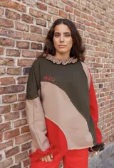Buzo de algodón con diseño de paneles asimétricos en colores verde oliva, beige y rojo. Presenta cuello con volados, bordado con la palabra 'azu' en el pecho y puños con volados en color rojo.