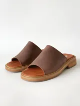 Sandalias de cuero color chocolate, con faja ancha en el empeine, plantilla de gamuza y suela plana con taco bajo.
