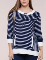 Buzo liviano de estilo deportivo-marinero y silueta semi holgada, confeccionado en tejido acanalado con diseño a rayas horizontales y verticales en azul marino y blanco. Cuenta con escote redondo amplio, cordón ajustable, bolsillo frontal tipo canguro, mangas tres cuartos con puños anchos y aberturas laterales en el ruedo.