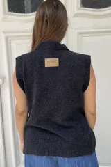 Chaleco de lana color crema con diseño de flor bordada en relieve en el frente, cuello redondo y aberturas laterales en el ruedo.