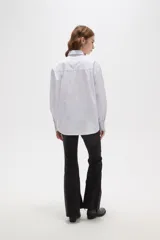 Camisa de algodón a rayas verticales, con cuello camisero, cierre frontal de botones y detalle de strass aplicado en la parte superior delantera.