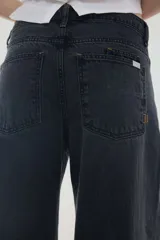 Pantalón jean gris oscuro de tiro medio y piernas anchas, con diseño de cinco bolsillos y cierre frontal con botón y cremallera.