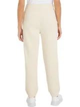 Pantalón de jogging color crema, con cintura elástica y cordón ajustable. Presenta un logo circular con el monograma TH bordado en azul en el muslo.