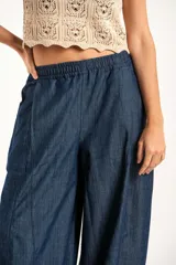 Pantalón tipo jean de corte wide leg y diseño balloon, con cintura elástica y cordones ajustables en los tobillos. Confeccionado en algodón denim de tono azul oscuro.