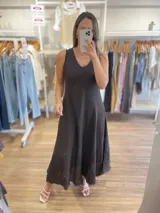 Vestido largo sin mangas, color beige claro, con escote en V y textura arrugada o arrugada, con terminación deshilachada en el ruedo.