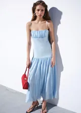 Vestido midi celeste de lino con escote recto, tirantes finos, cuerpo fruncido y falda evasé con volados.