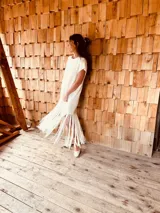 Vestido tejido color blanco con hilo metalizado, corte oversized, mangas cortas y flecos en el ruedo.