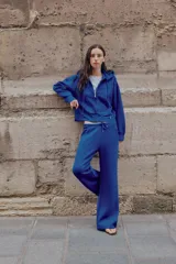 Pantalón flare de tiro medio, color azul, confeccionado en tejido de punto elástico. Cuenta con cintura elástica ajustable con cordón, bolsillos delanteros y corte amplio en las piernas.