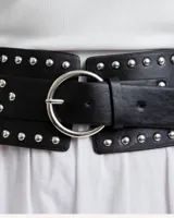 Cinto ancho de cuero sintético negro con tachas plateadas y hebilla circular plateada.