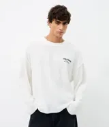 Remera de manga larga color blanco, confeccionada en tejido texturizado con elastano. Presenta un diseño minimalista con estampa lettering en el pecho y en la espalda.