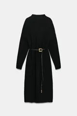 Vestido midi de punto color marrón oscuro, con cuello perkins y manga larga. Presenta un diseño holgado que se ajusta a la cintura mediante un cinturón fino de cuero sintético con hebilla metálica dorada.