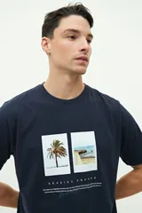 Remera de manga corta color azul marino, con corte regular y estampa frontal con dos fotografías de paisajes costeros y texto alusivo.