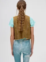 Chaleco de denim liviano con cierre frontal de botones metálicos, detalle de apliques metálicos verticales y ruedo con terminación desflecada.