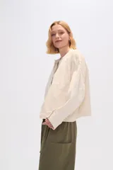 Chaqueta color crema de algodón con cuello mao, cierre frontal con botones, bolsillos laterales y mangas largas.