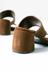 Sandalias tipo mule de taco medio, confeccionadas en cuero gamuzado color terracota. Presentan dos tiras anchas con detalles de costuras pespunteadas en los bordes y taco cuadrado estable.