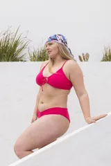 Conjunto de bikini rosado con corpiño triangular con lazo en el centro y bombacha clásica con corte en V.