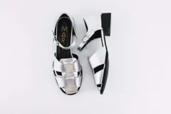 Sandalias plateadas de cuero con tiras entretejidas en el empeine, pulsera con hebilla al tobillo, punta almendrada y tacón cuadrado bajo.