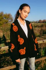 Cárdigan negro de lana merino con bordados de flores color naranja.
