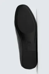 Mocasín de cuero negro, de estilo clásico y minimalista, con suela fina y horma cuadrada.