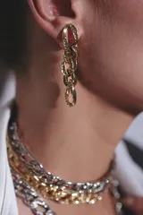Aros colgantes dorados en forma de cadena eslabonada, decorados con cristales incrustados en su superficie.